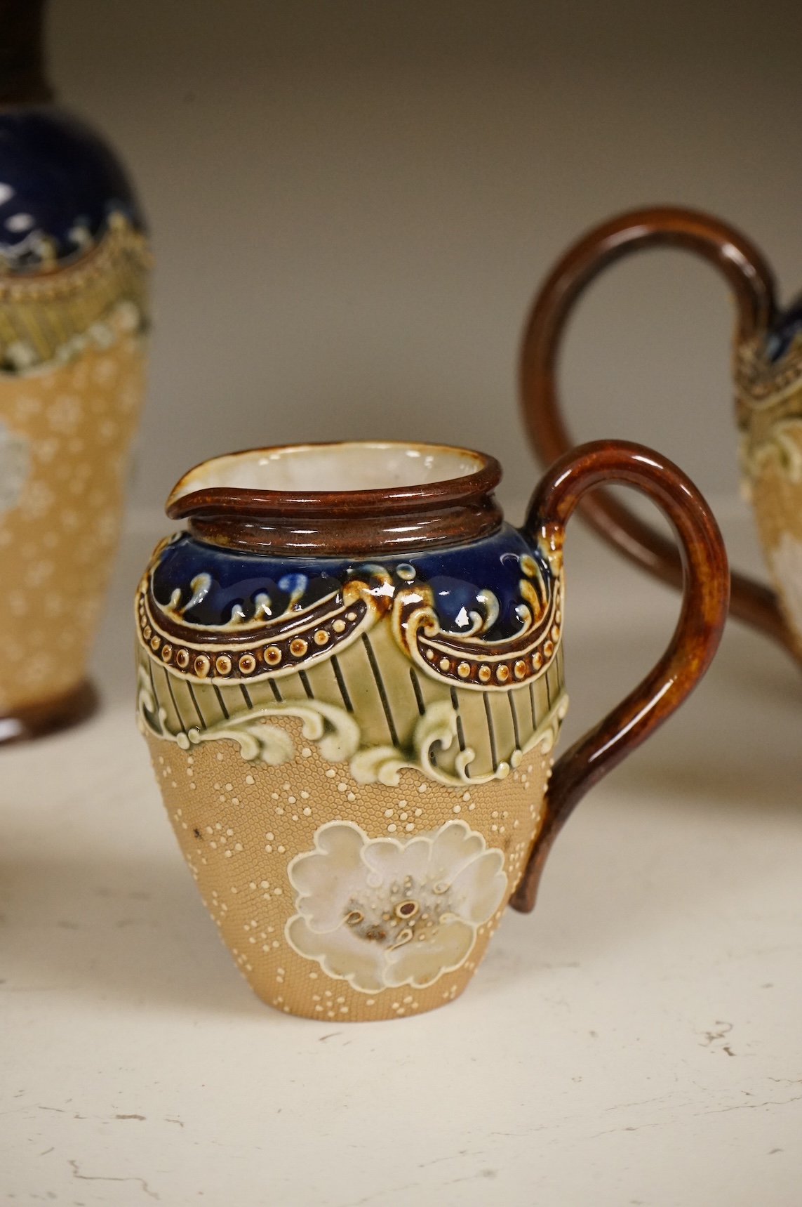 A small collection of Doulton Lambeth stoneware comprising, tea and coffee pots, two jugs and sugar bowl, largest 21cm high